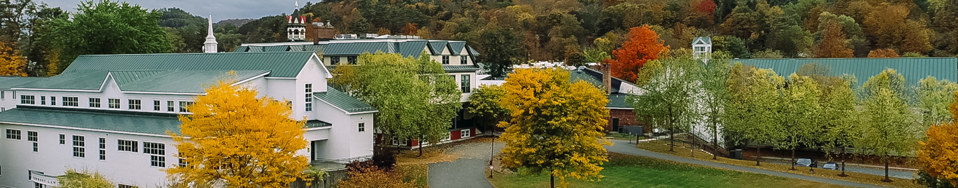 Image of Vermont Law and Graduate School campus buildings including Oakes Hall to the left, DeBevoise and the back lawn in the middle and the Julien and Virginia Cornell Library hidden behind fall color trees.